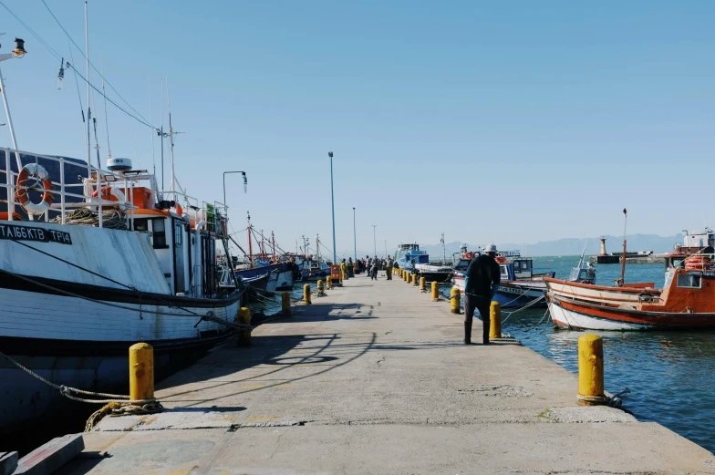 people standing on pier with boats and boats next to it