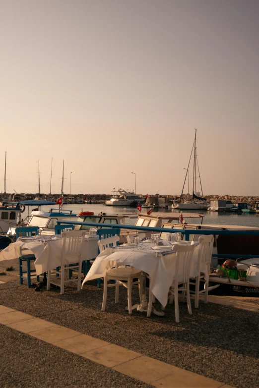 a large number of white tables and chairs near some water