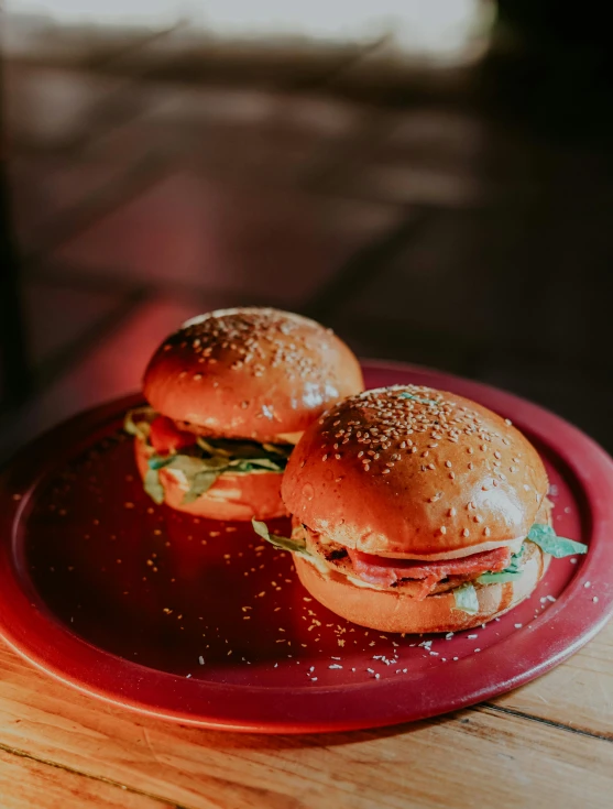 two small hamburgers sitting on a red plate