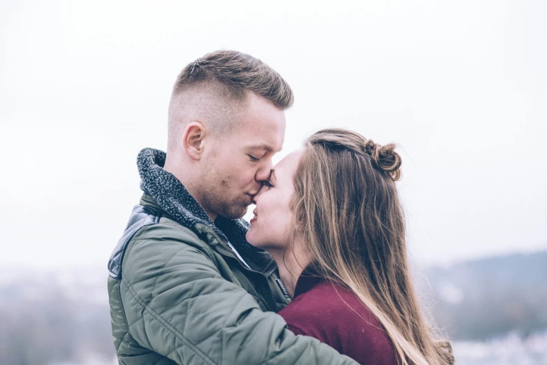 two people kissing with fog and trees in the background