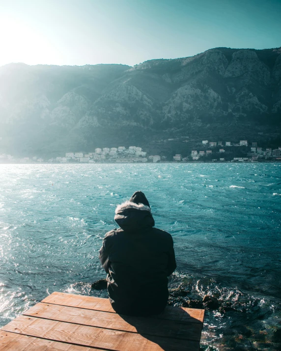 a person sits on a dock overlooking the water