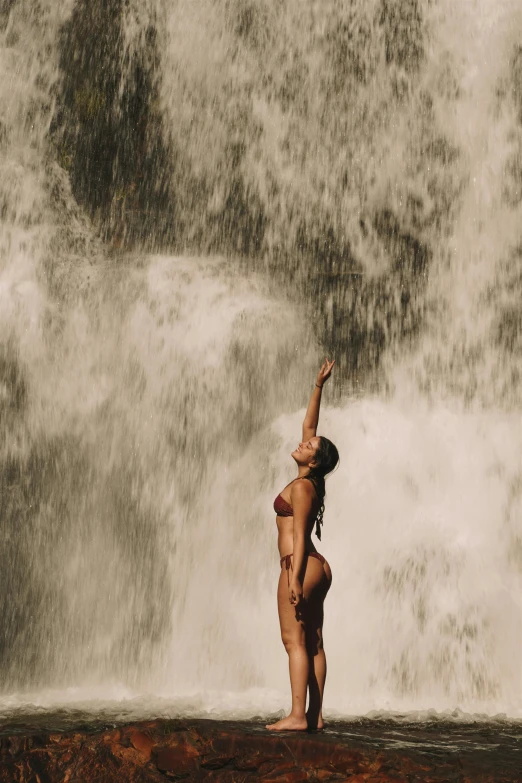 the young woman is dancing by the large waterfall