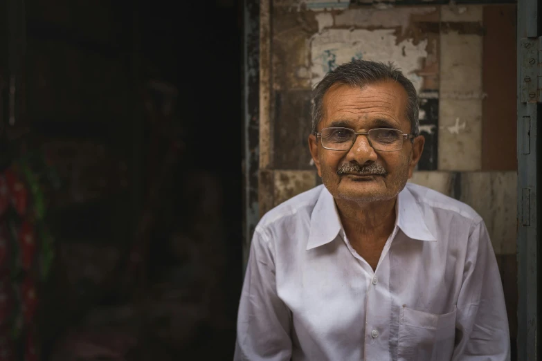 a man wearing glasses in a dirty room