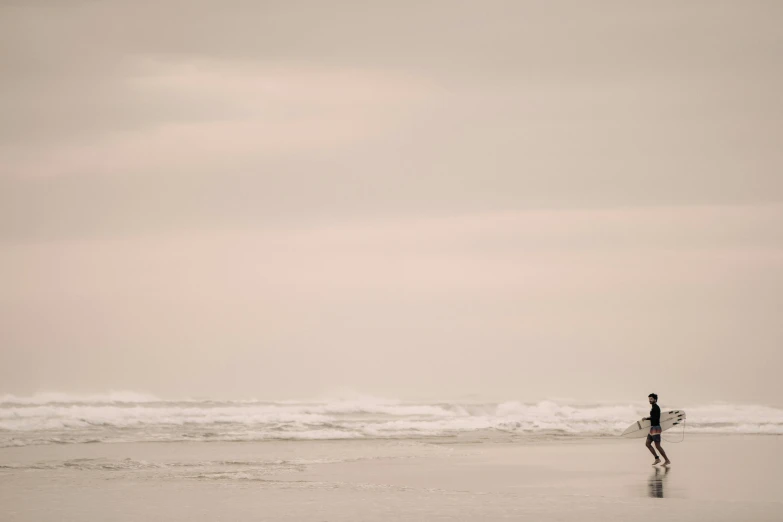 a man on a beach holding a surfboard