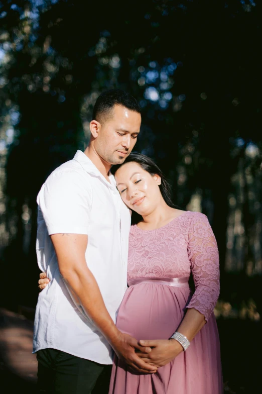 a man and a woman cuddle on their stomach in the woods