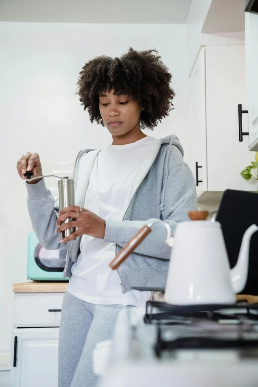 a woman holding a cup of coffee while standing in a kitchen