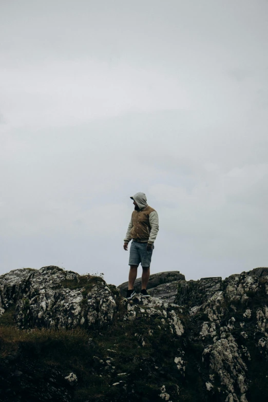 a man wearing a hat and backpack is standing on a rock