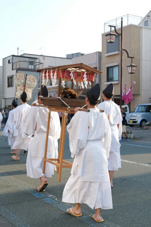 group of men walking past a shrine carrying soing