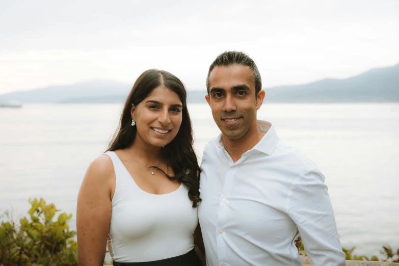 two people standing near one another in front of water