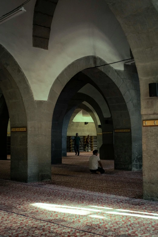 an empty hallway with people sitting on the floor