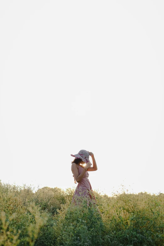 the woman has a large hat standing in a field