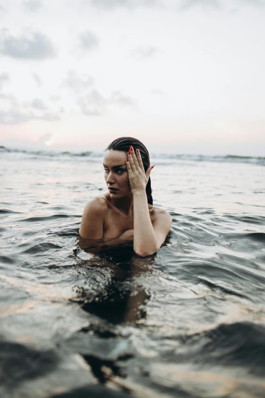 a man in the water holds his hand up to his face