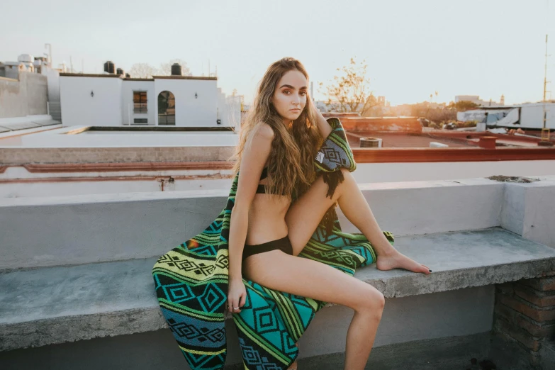 a woman in bathing suits sits on a cement ledge