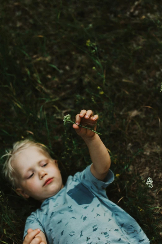 a little boy laying on the grass playing with a frisbee