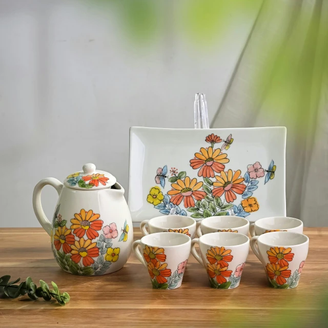 a tea set that has orange flowers on the side