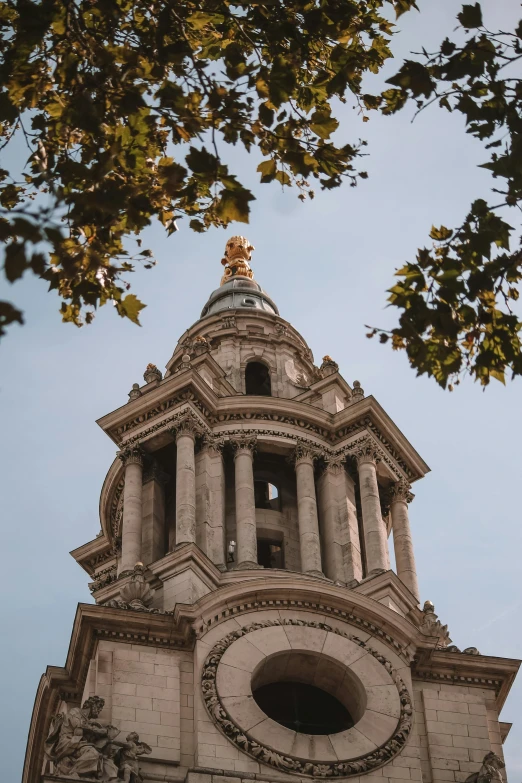 a clock tower sitting below a tree in the blue sky