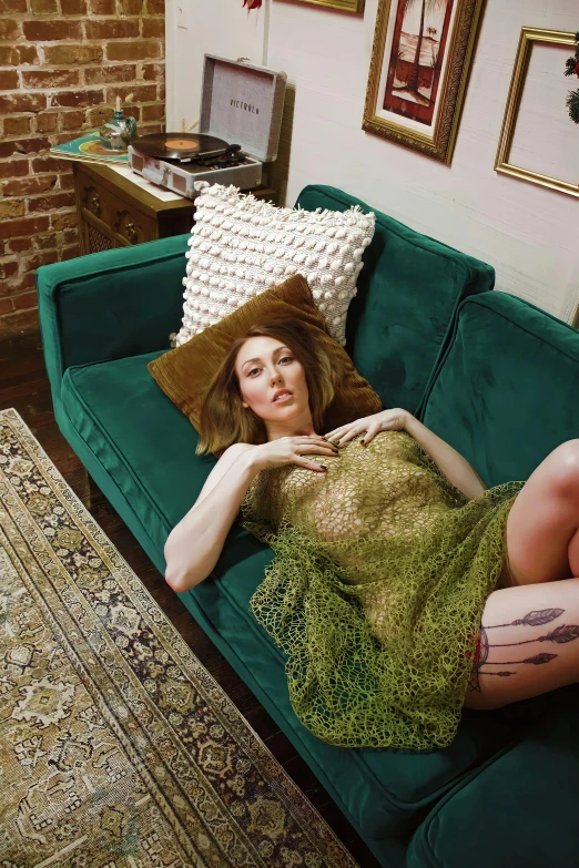 a woman is laying on a green couch