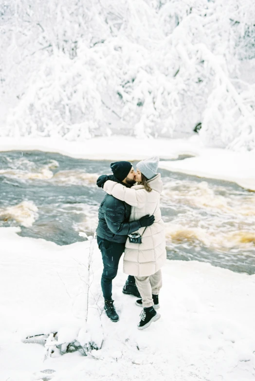 man and woman emce in the snow by a mountain