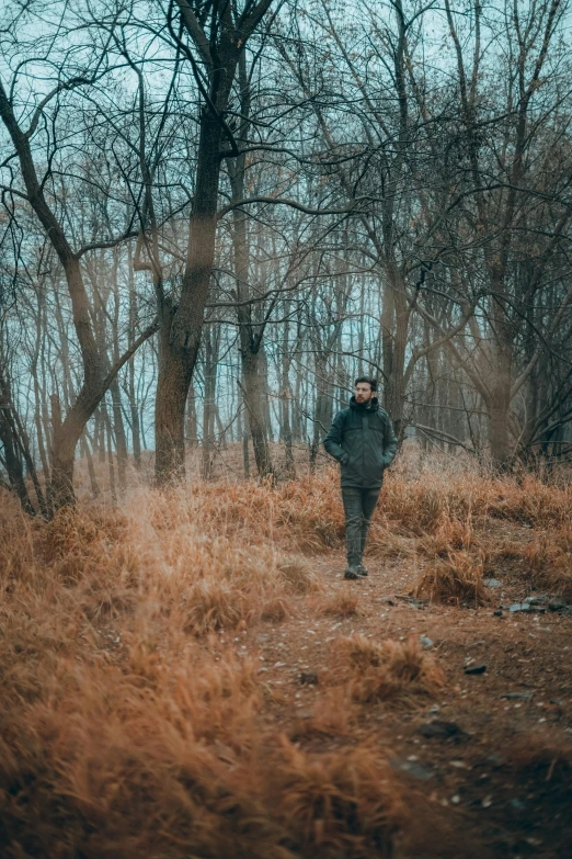 a man walking along side a tree covered field