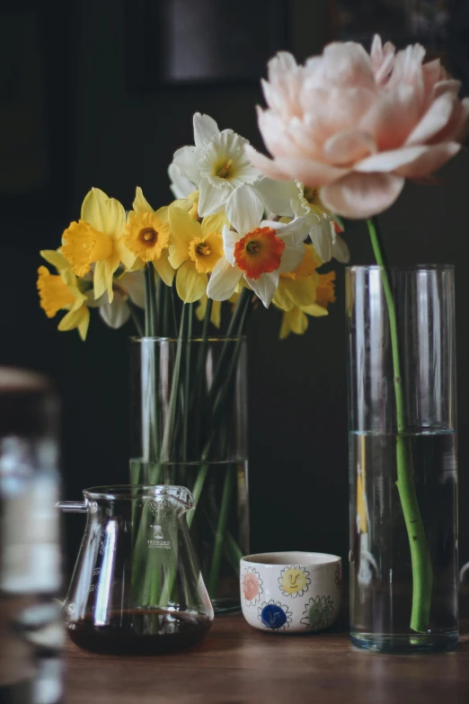vases and cups sit on a table with flowers