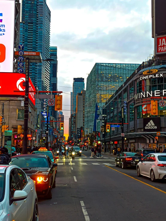 cars driving down a crowded city street at dusk