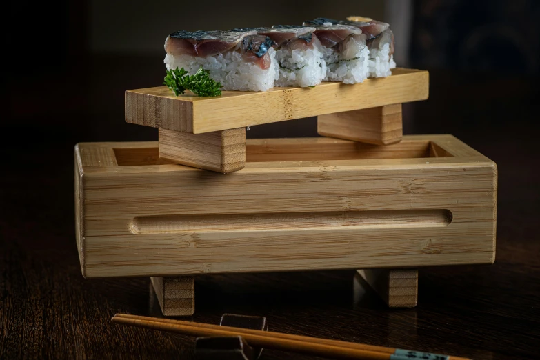 a wooden case that is holding sushi and chopsticks