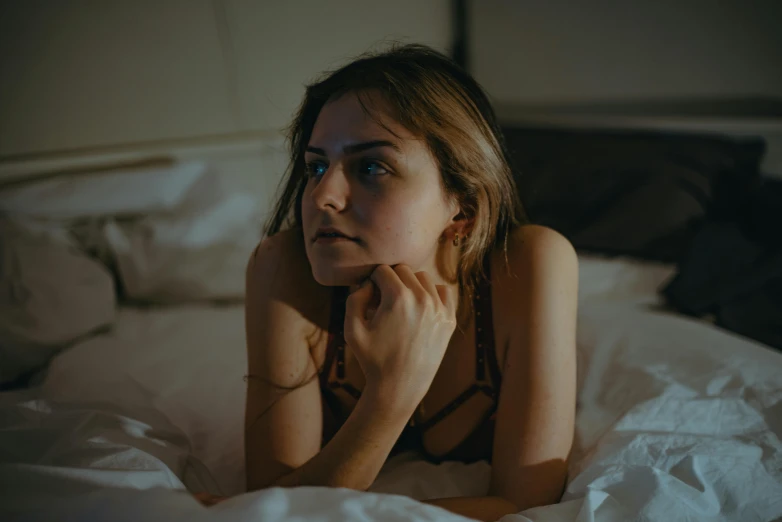 a woman laying on a bed under white sheets