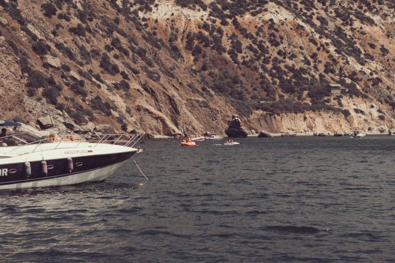 boat in the water near a mountain, next to some boats