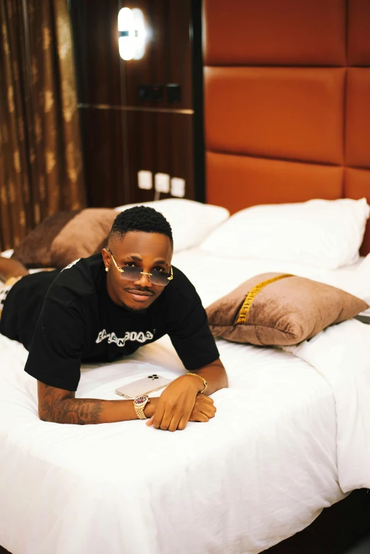 a man in black shirt laying on a white bed