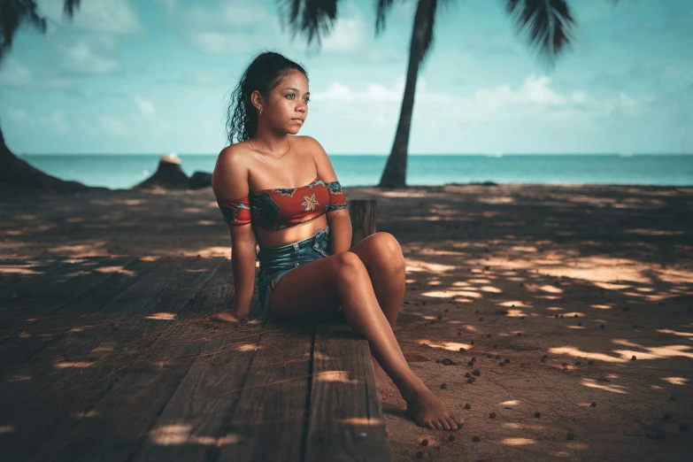 woman sitting on a wooden bench on the beach with palm trees