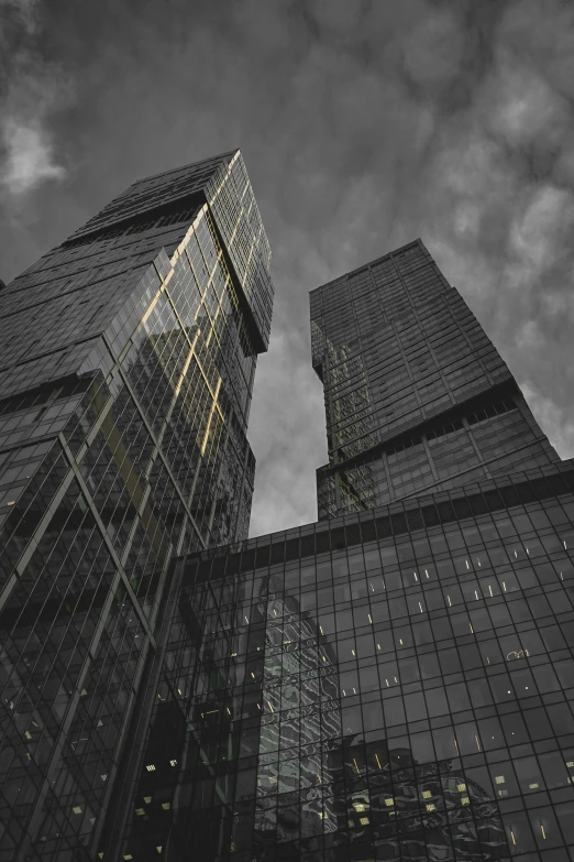 some large buildings with lights on against a cloudy sky