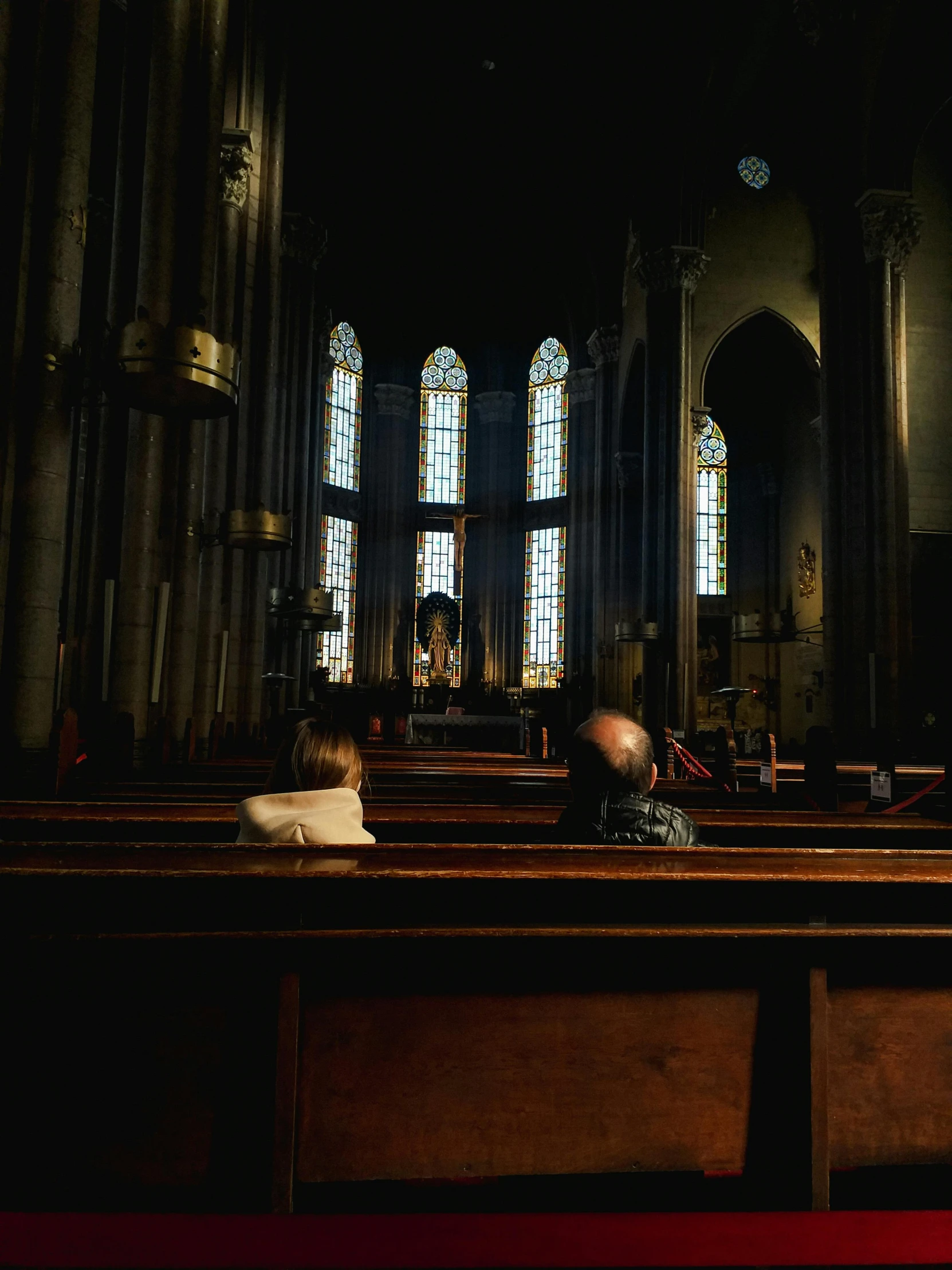a dark cathedral with tall windows and pews