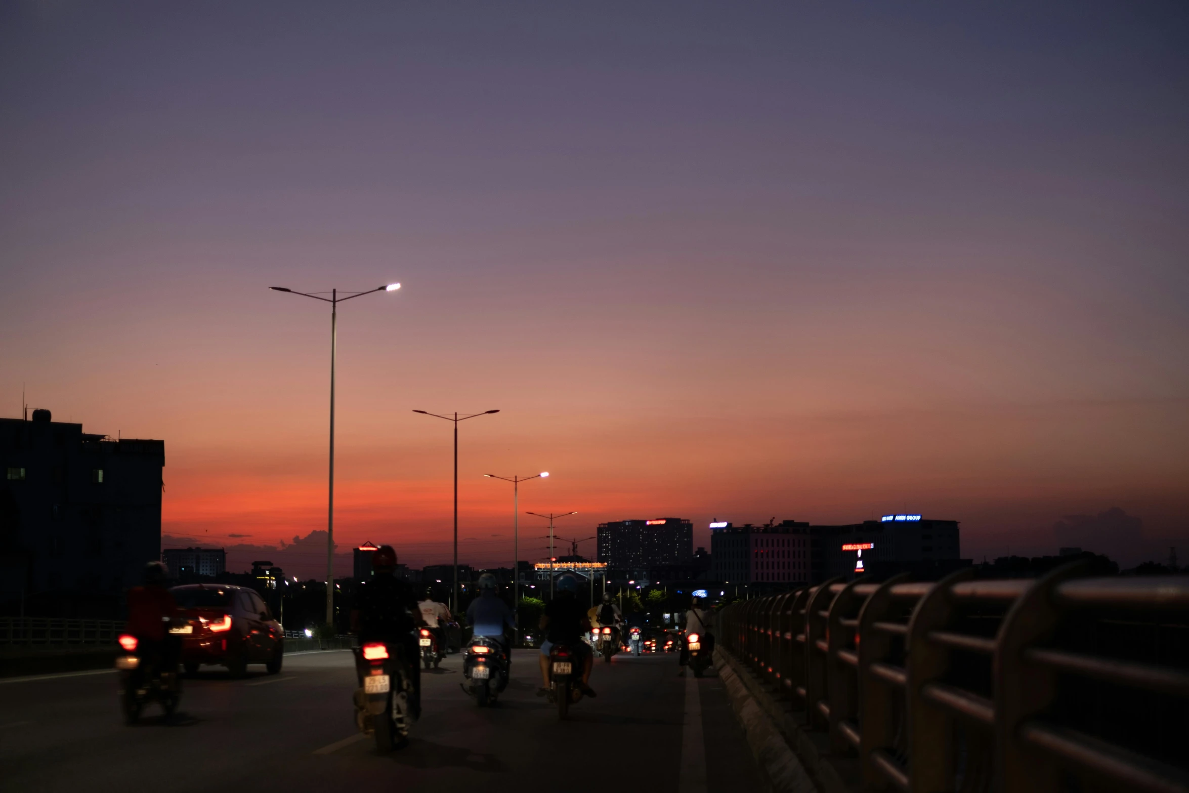 people riding bikes down a street at dusk