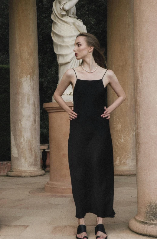 a young lady is standing outside wearing a black dress