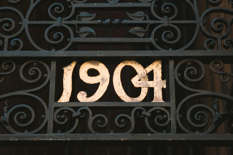 an iron gate has an ornamental frame with numbers nineteen - nine