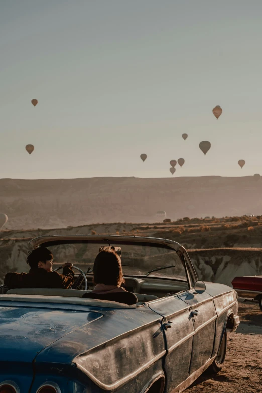 two people riding in an old car with  air balloons