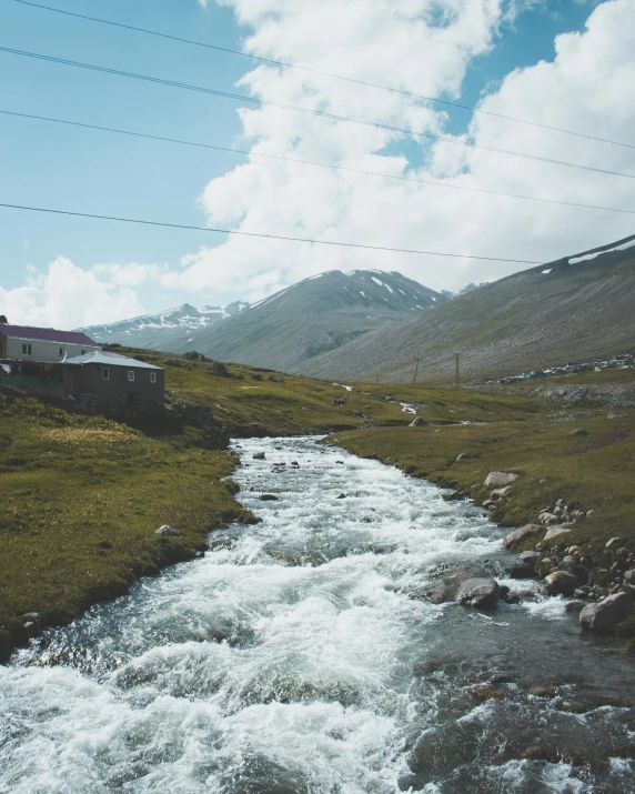 a river flowing in a rural valley near a small building