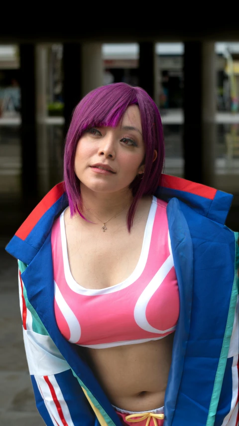 a woman with bright pink hair in a pink bikini top and colorful scarf