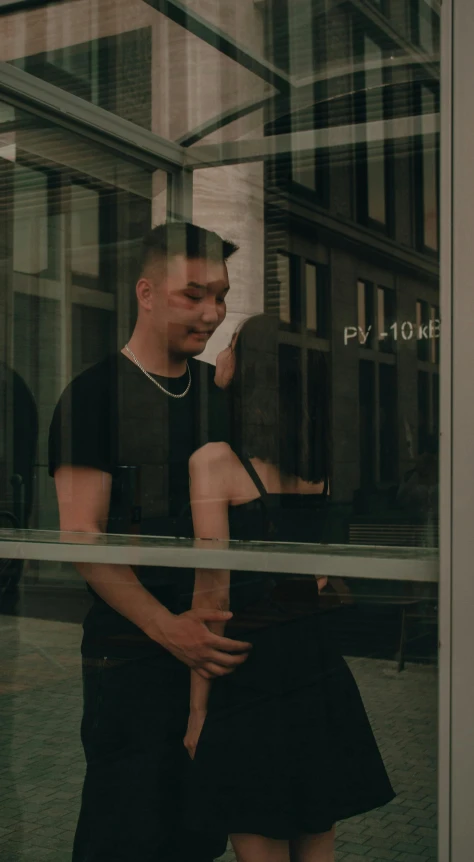 a man and a woman stand beside each other in front of a glass wall