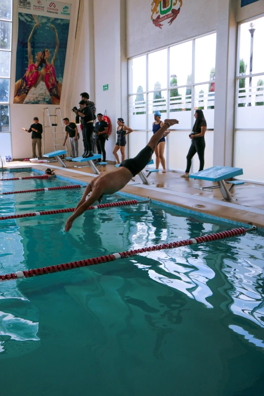 a man in black is standing at the edge of a pool diving