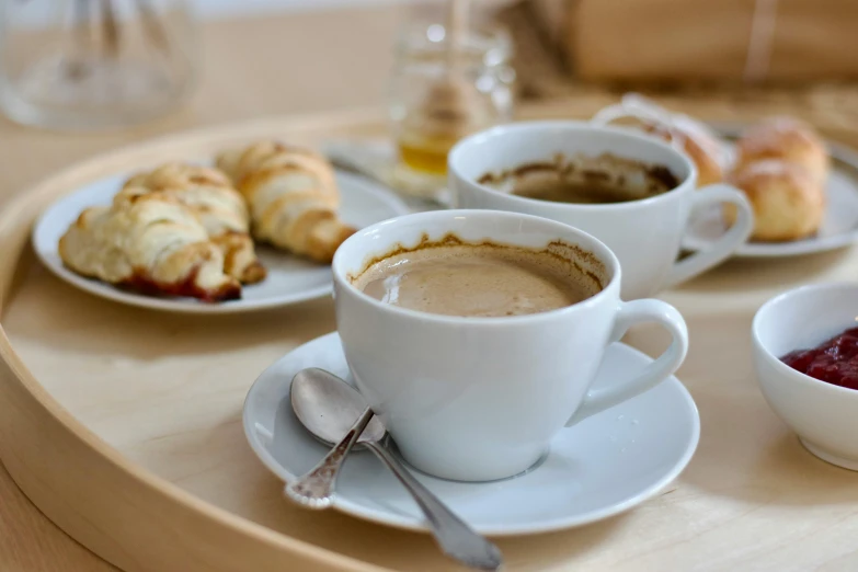 coffee in cups and saucers sit on a tray