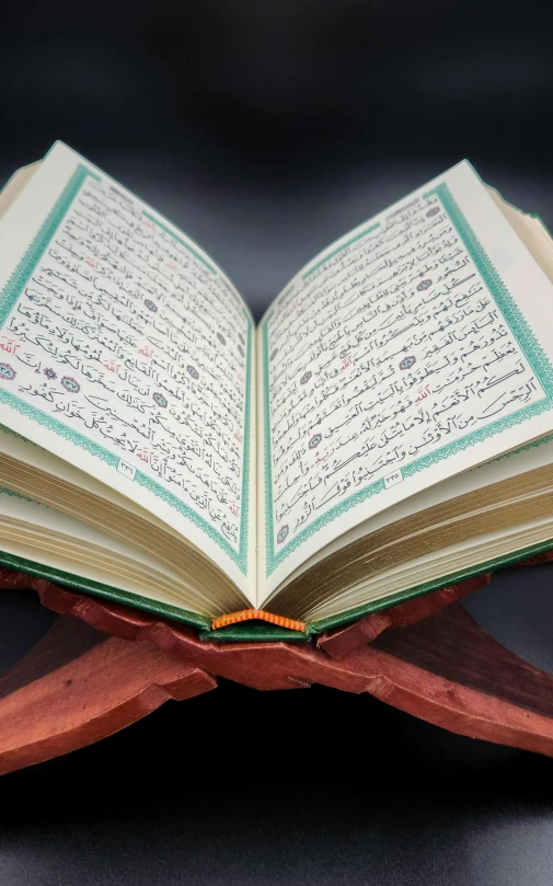 the open muslim book is lying on a wooden stand