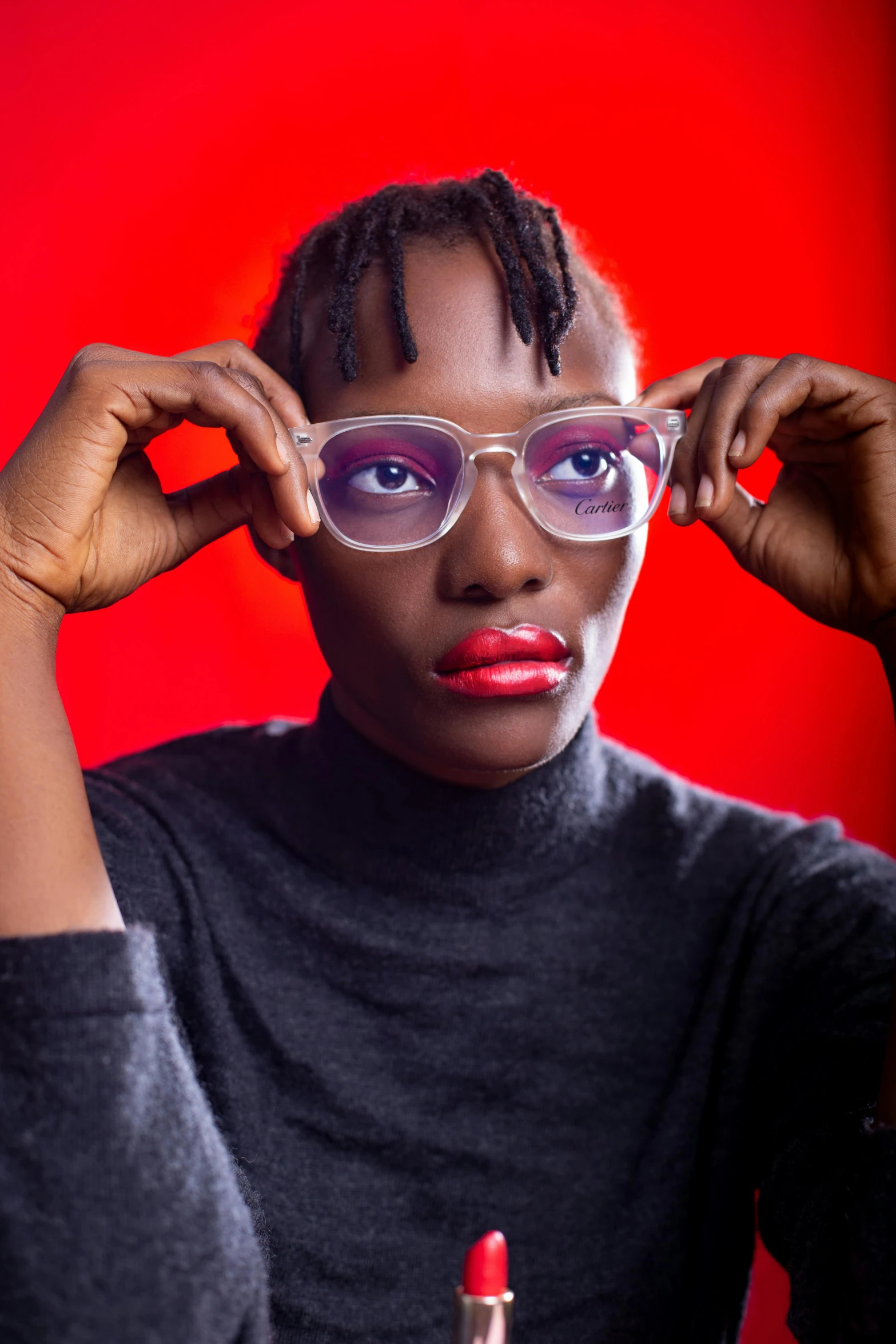 a woman with glasses holding her hands near her eye