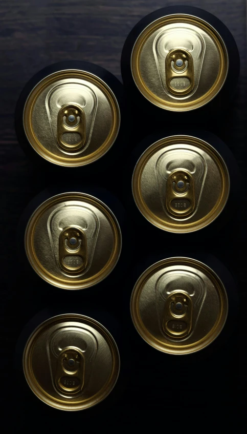 four gold soda soda can lids sitting on top of a black counter