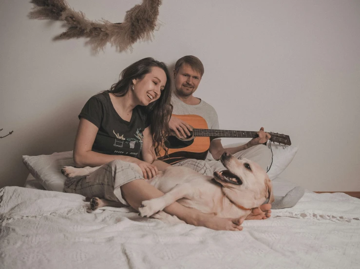 the man and woman are on the bed with the dog