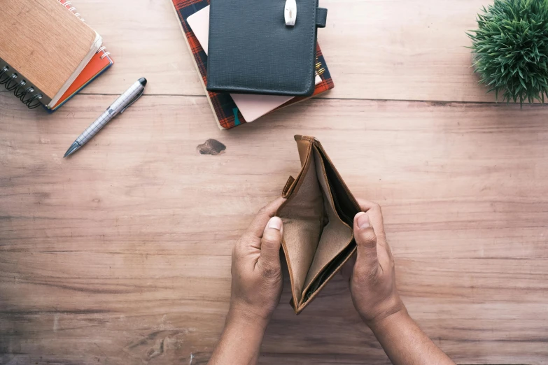 two hands holding up a small leather wallet