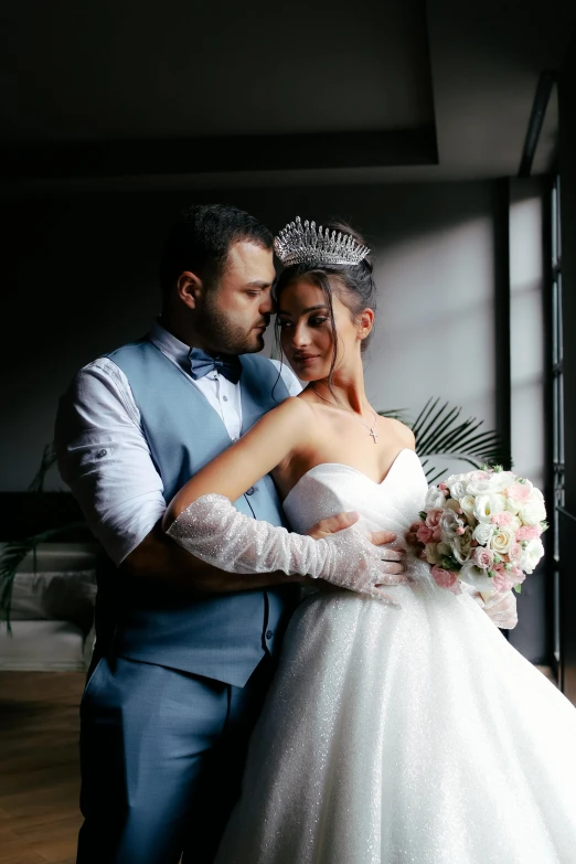 a bride and groom are hugging in a room