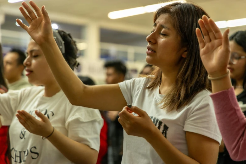 a group of young people praying with hands raised in the air