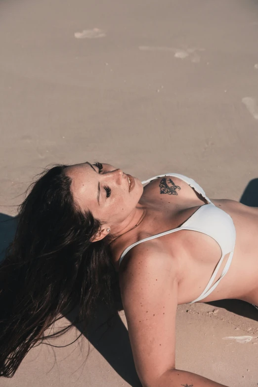 woman lying on beach in bikini with sun in background
