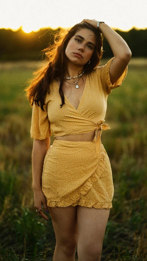 a woman in a dress poses in the middle of a field